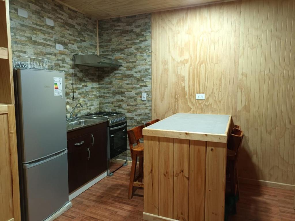 a kitchen with a refrigerator and a stove at Cabaña Los Raulies, Neltume in Puerto Fuy