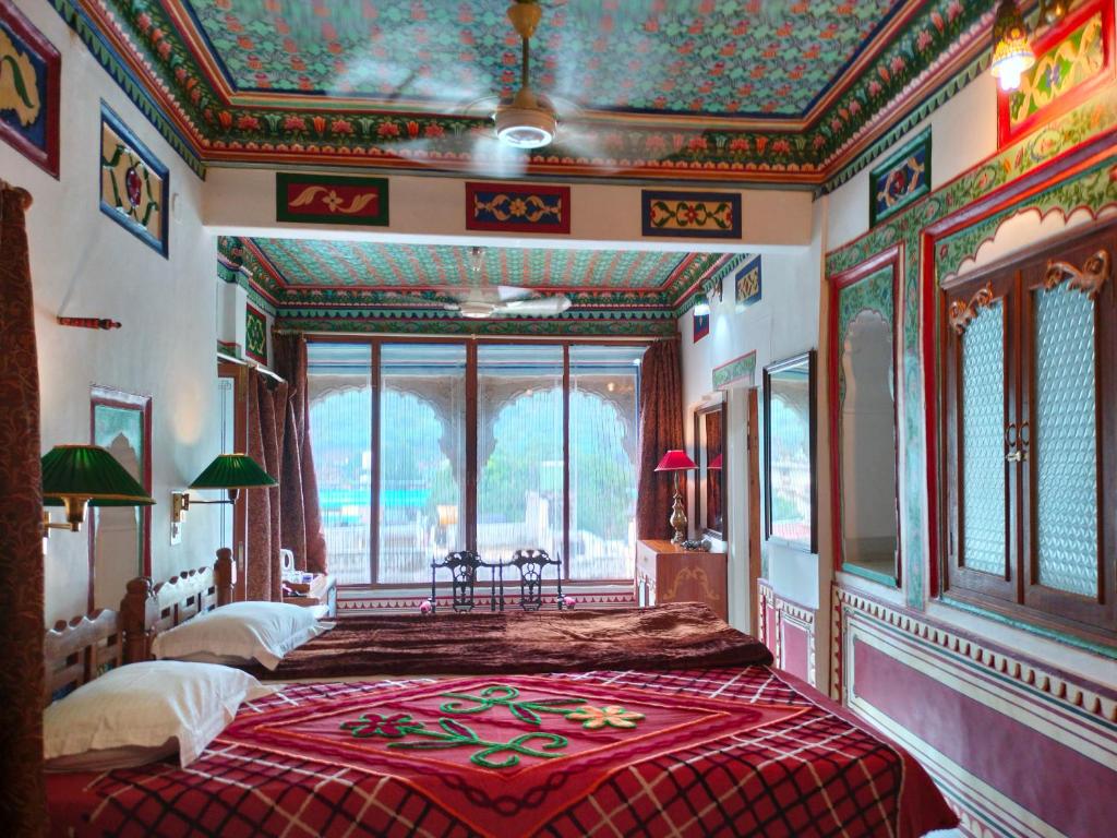 a bedroom with two beds and a large window at Haveli Braj Bhushanjee Heritage Hotel in Būndi