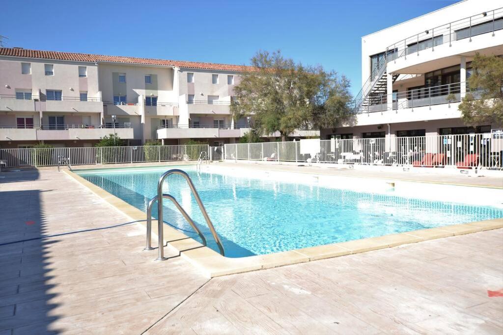 une piscine avec toboggan en face d'un bâtiment dans l'établissement Cap sur la Méditerranée et la Camargue, au Grau-du-Roi