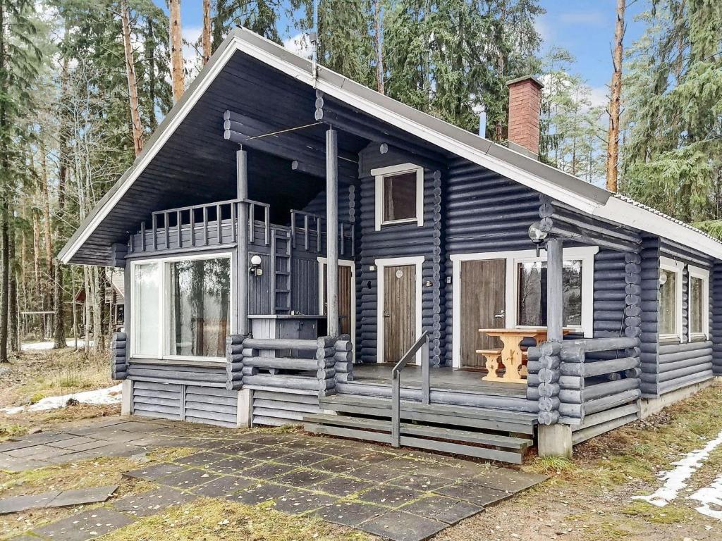 a blue cabin in the woods with a porch at Holiday Home Linnusmaa by Interhome in Torvoila