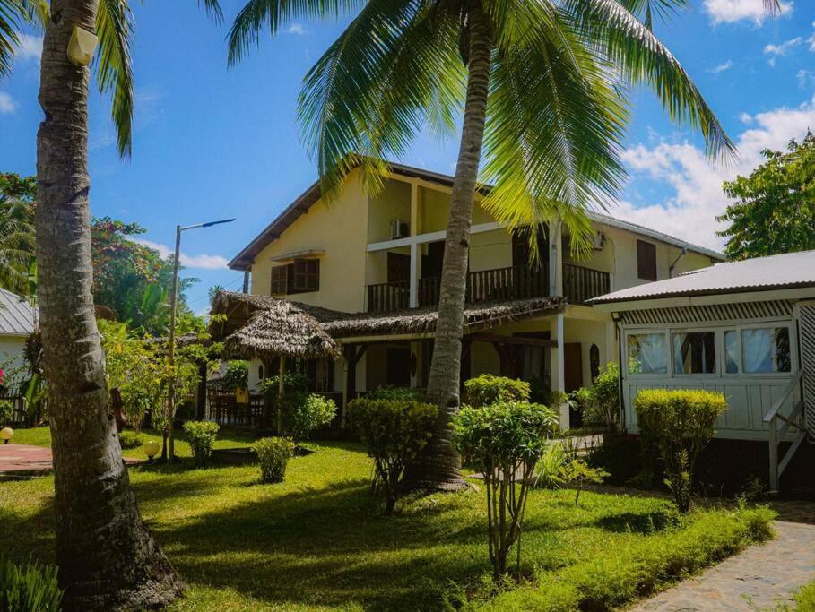 a house with palm trees in front of it at Villa Carla, vacances à la mer in Nosy Be