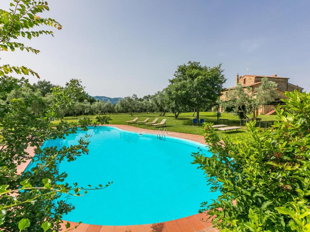 a large blue swimming pool in a yard with trees at Apartment Rosmarino by Interhome in Sorano
