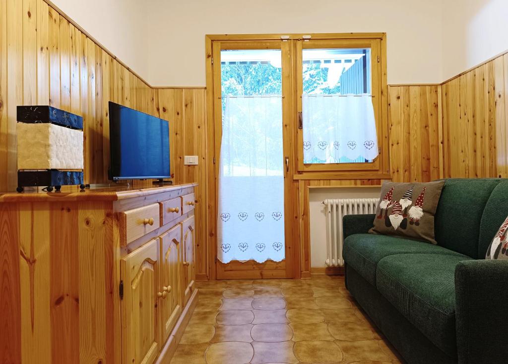 uma sala de estar com um sofá verde e uma televisão em Collalto Guest House em Piancavallo