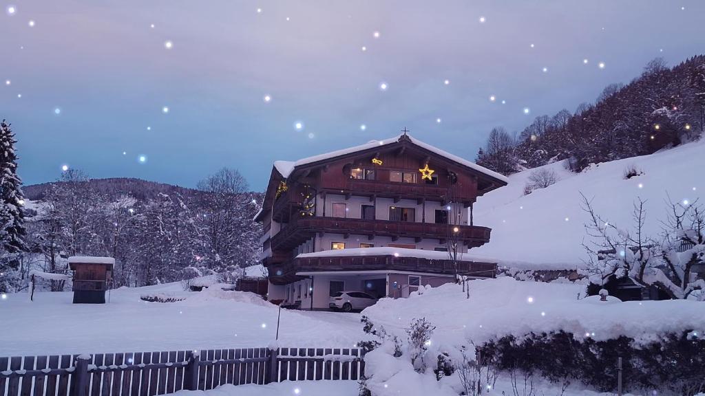 ein großes Gebäude im Schnee mit Schneeionage in der Unterkunft Appartement Maurer in Niederau