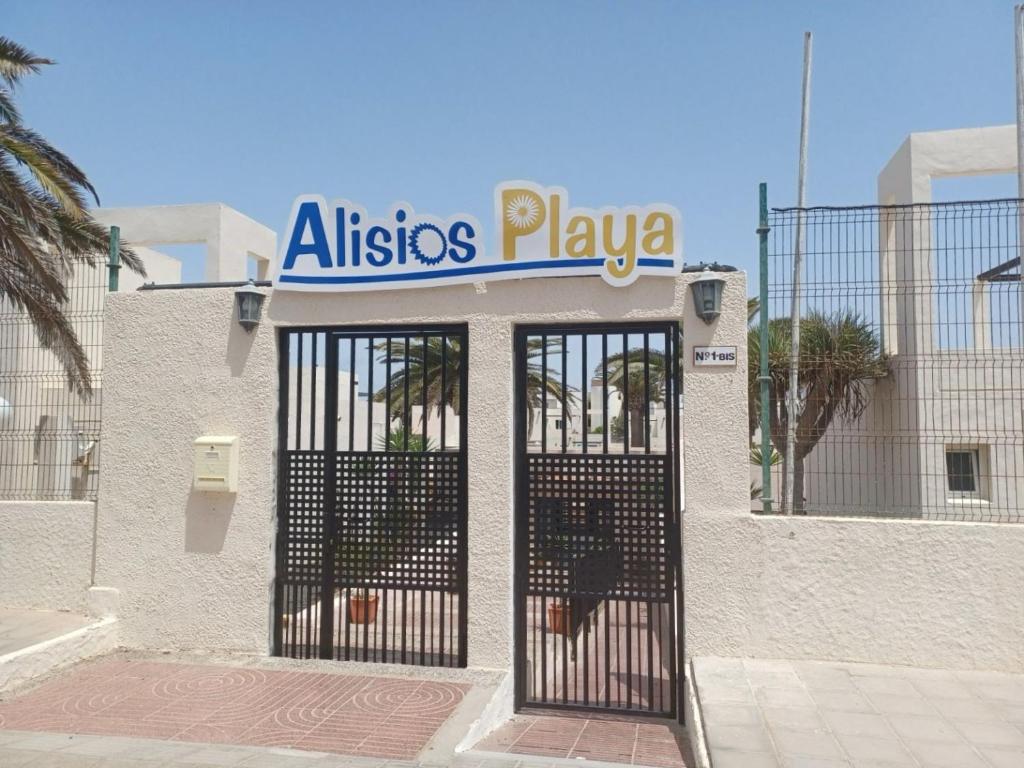 a building with a gate with a sign on it at Alisios Playa, pool view in Corralejo
