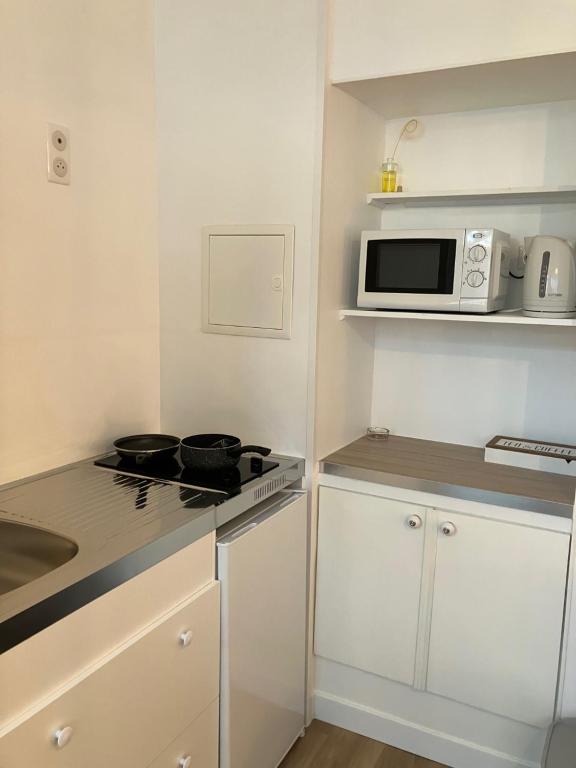 a small kitchen with a stove and a microwave at Manava Villa vue mer et Mont Saint Michel piscine intérieure in Saint-Jean-le-Thomas
