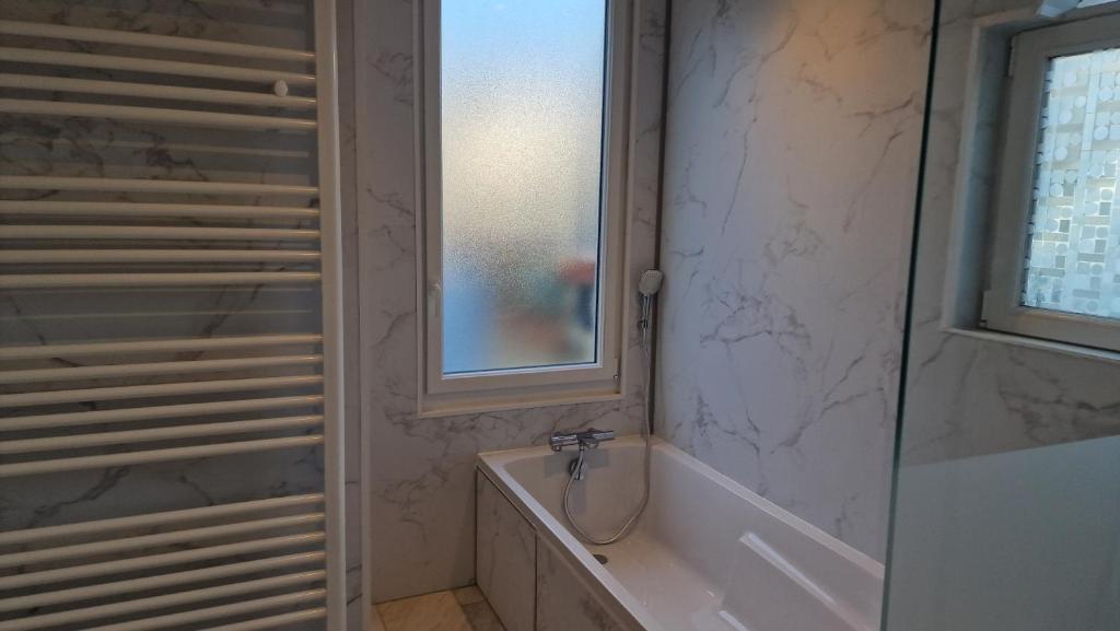 a bathroom with a bath tub and a window at Manava Villa vue mer et Mont Saint Michel piscine intérieure in Saint-Jean-le-Thomas