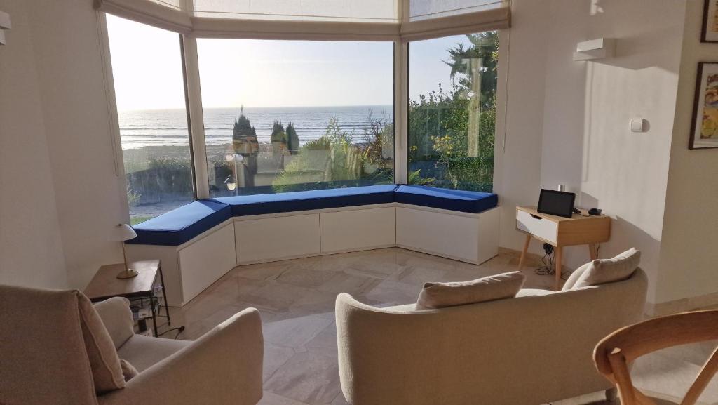 a living room with a large window with a view of the ocean at Manava Villa vue mer et Mont Saint Michel piscine intérieure in Saint-Jean-le-Thomas