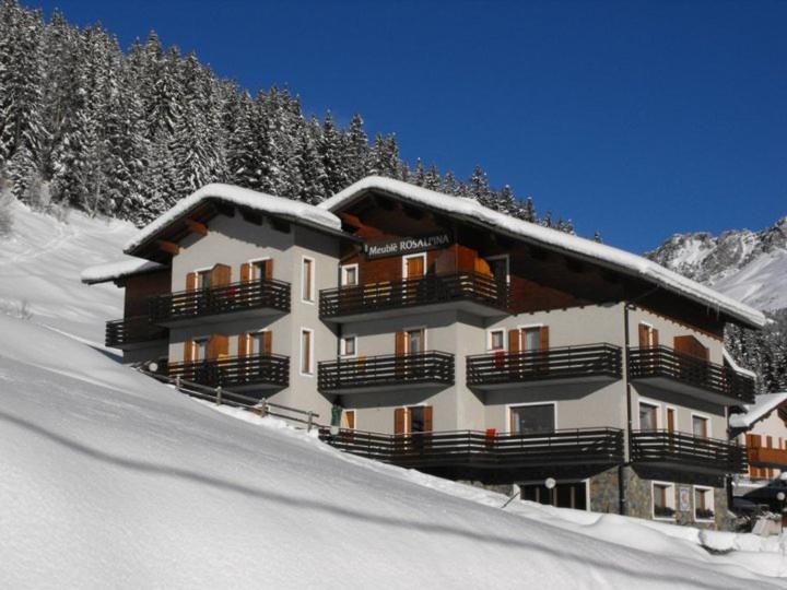 un grand bâtiment avec de la neige sur le flanc d'une montagne dans l'établissement Meublè Rosalpina, à Valdidentro