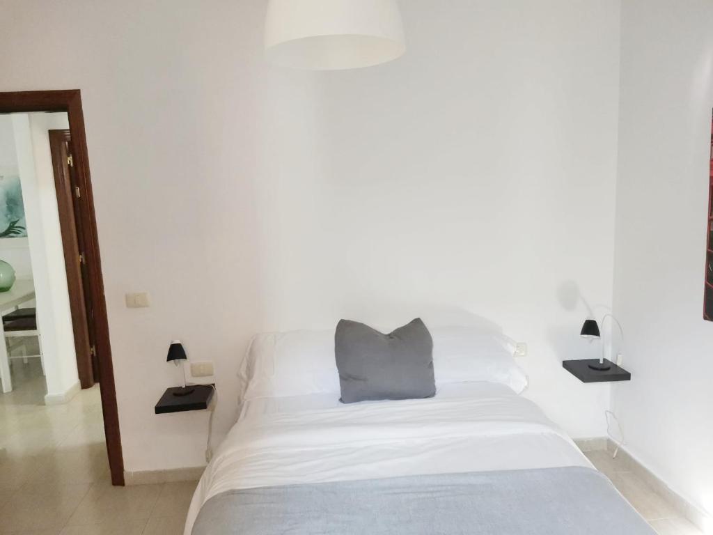 een wit bed met een grijs kussen erop bij Apartamento Triana in Los Silos