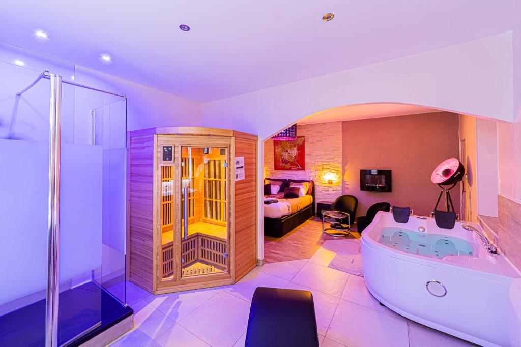 1 dormitorio con 1 cama y baño con bañera. en Suite Romantique & Spa, en Dijon