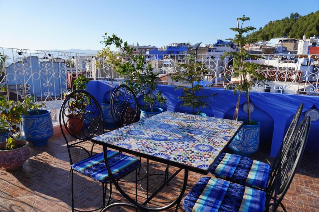 une table et des chaises assises sur un balcon dans l'établissement RIAD CHENGLI 蓝城里, à Chefchaouen