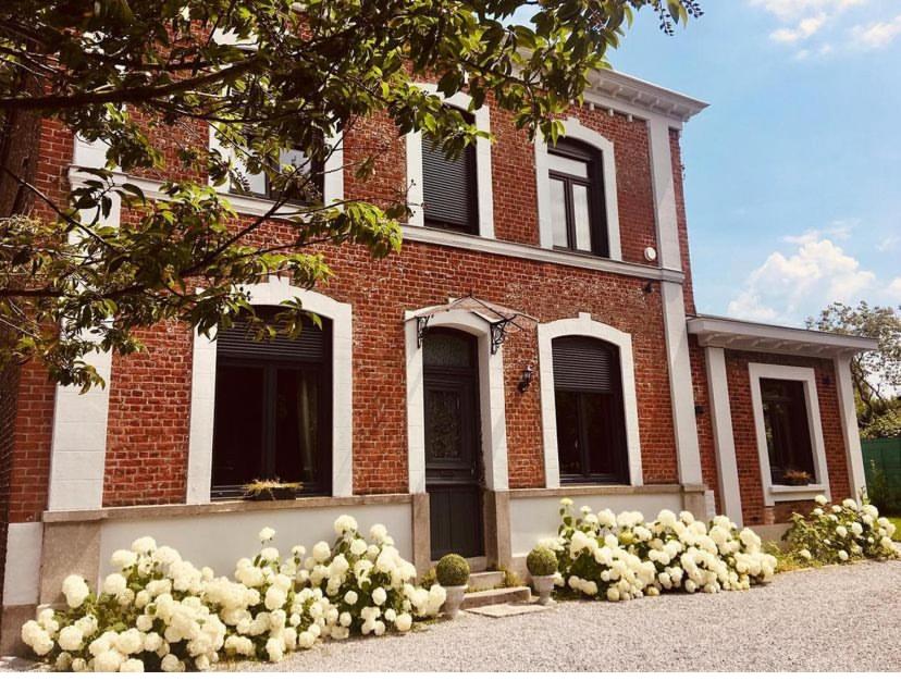 une maison en briques avec des fleurs blanches devant elle dans l'établissement La Green suite, à Lys-lès-Lannoy