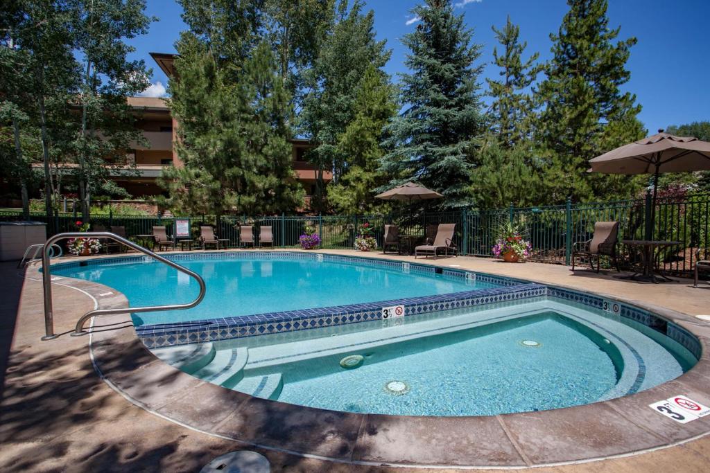 a swimming pool at a resort with chairs and an umbrella at Canyon Creek in Steamboat Springs