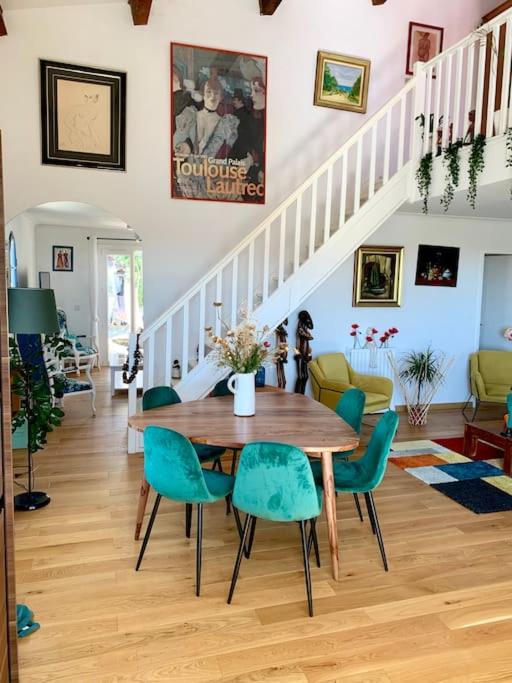 une salle à manger avec une table en bois et des chaises bleues dans l'établissement Charmante villa avec une âme., à Pignan
