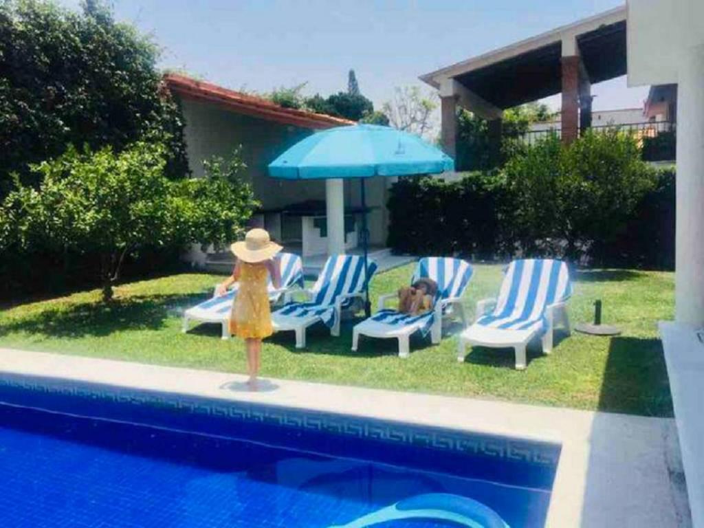 una mujer con un vestido amarillo de pie junto a las sillas y un paraguas en Lomas de Cocoyoc , Family- Friendly, en Cocoyoc