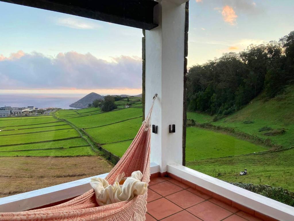 a hammock on a balcony with a view of a field at Spacious House with Sea View in Angra do Heroísmo in Angra do Heroísmo