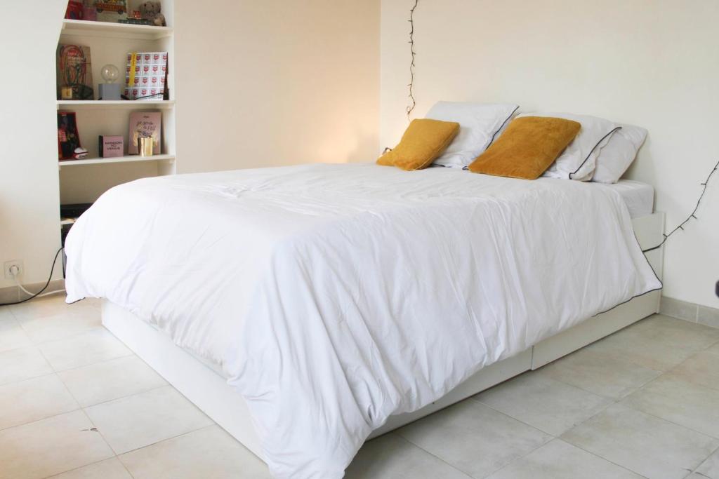 un letto bianco con lenzuola bianche e cuscini arancioni di 26 m love cocoon with Eiffel Tower view a Parigi