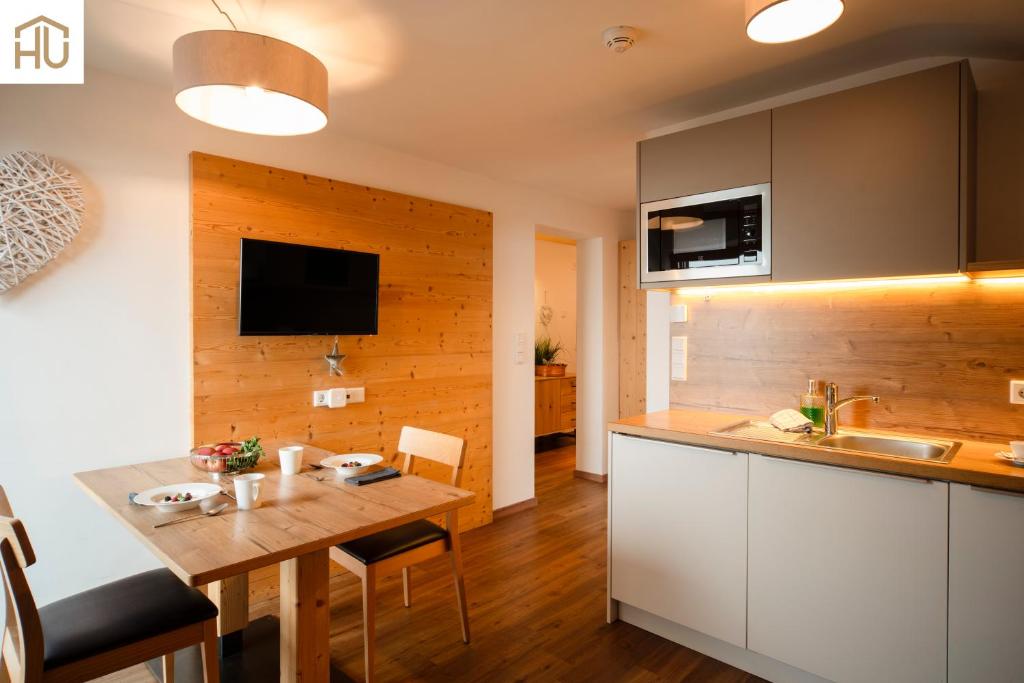 a kitchen with a wooden accent wall and a wooden table at Haus Percha Mountain Apartments in Perca