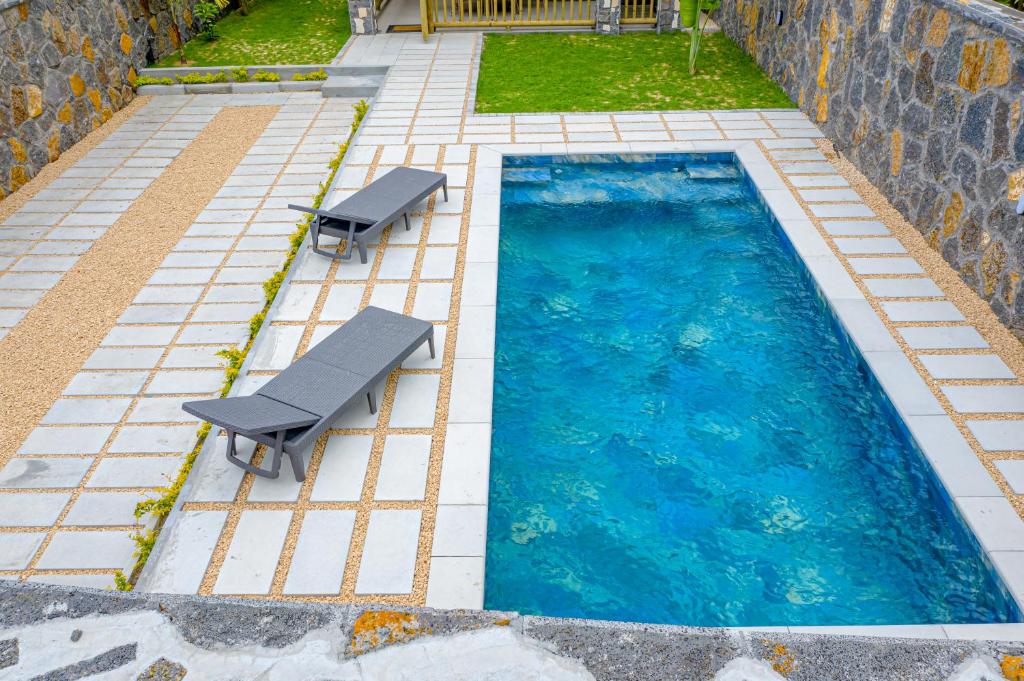 a swimming pool with two benches next to it at A&B Villa in Grand Baie