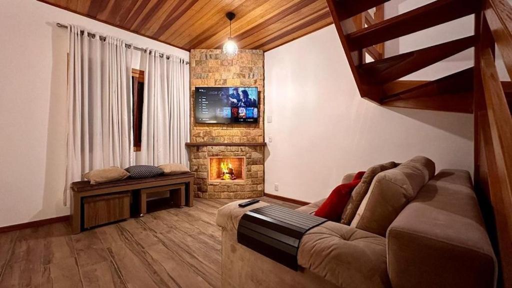 a living room with a couch and a fireplace at Chales Campestre Monte Verde - 150 mts do Centro in Monte Verde