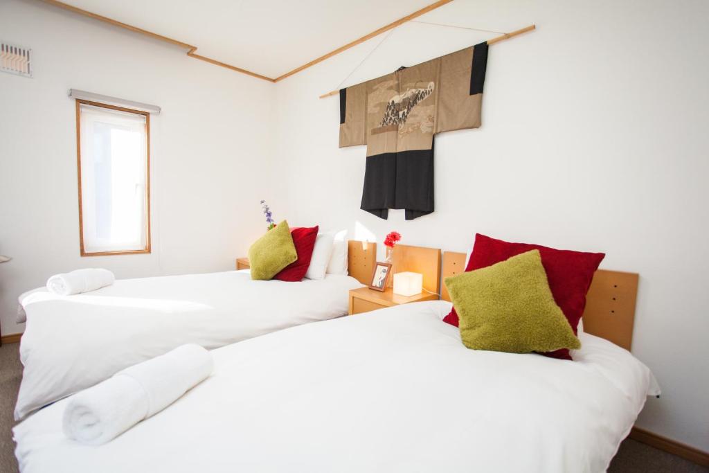 two beds in a room with white and red pillows at Yume House in Niseko