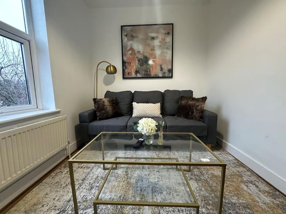 uma sala de estar com um sofá e uma mesa de vidro em Cosy Apartment in London em Londres