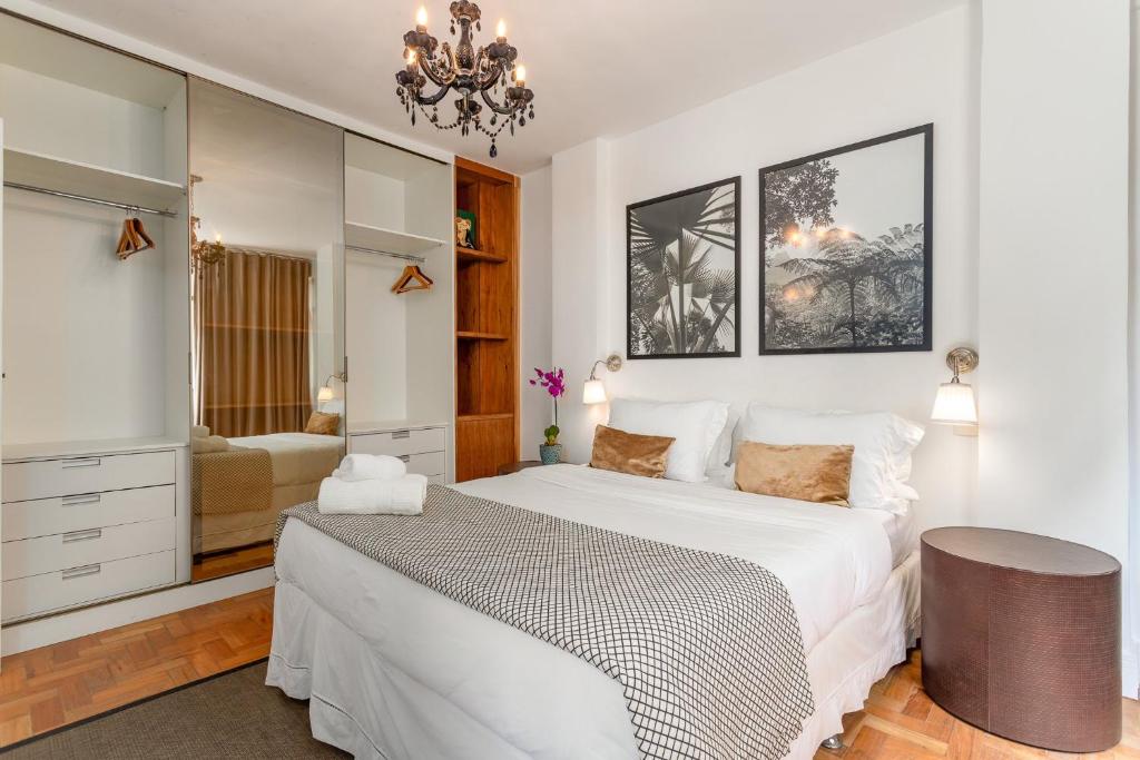 1 dormitorio con cama blanca y lámpara de araña en Unhotel - Apartamento Design no Leblon, Perto da Praia, en Río de Janeiro