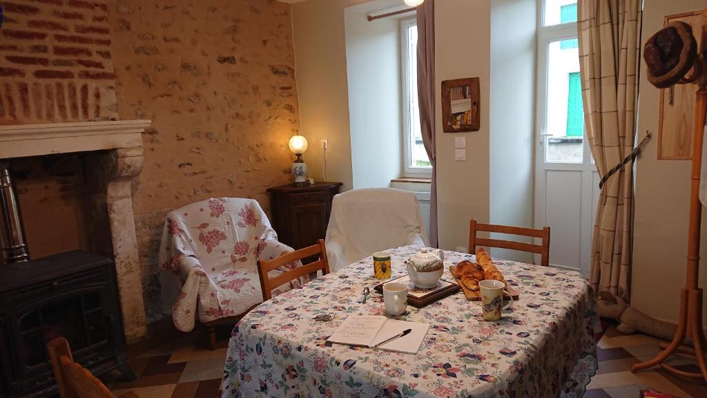 Le Gîte du Hérisson, Gîte de charme et de confort في Le Menoux: غرفة طعام مع طاولة ومدفأة