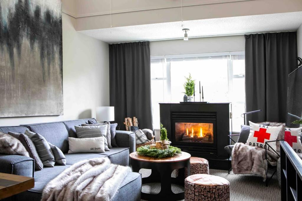 a living room with a blue couch and a fireplace at The Eden Whistler - Luxury 2 BDRM Ski in / Ski out in Whistler