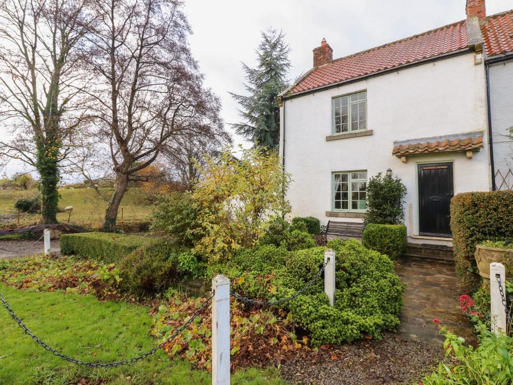a white house with a fence in the yard at Malt Shovel Cottage in Bedale
