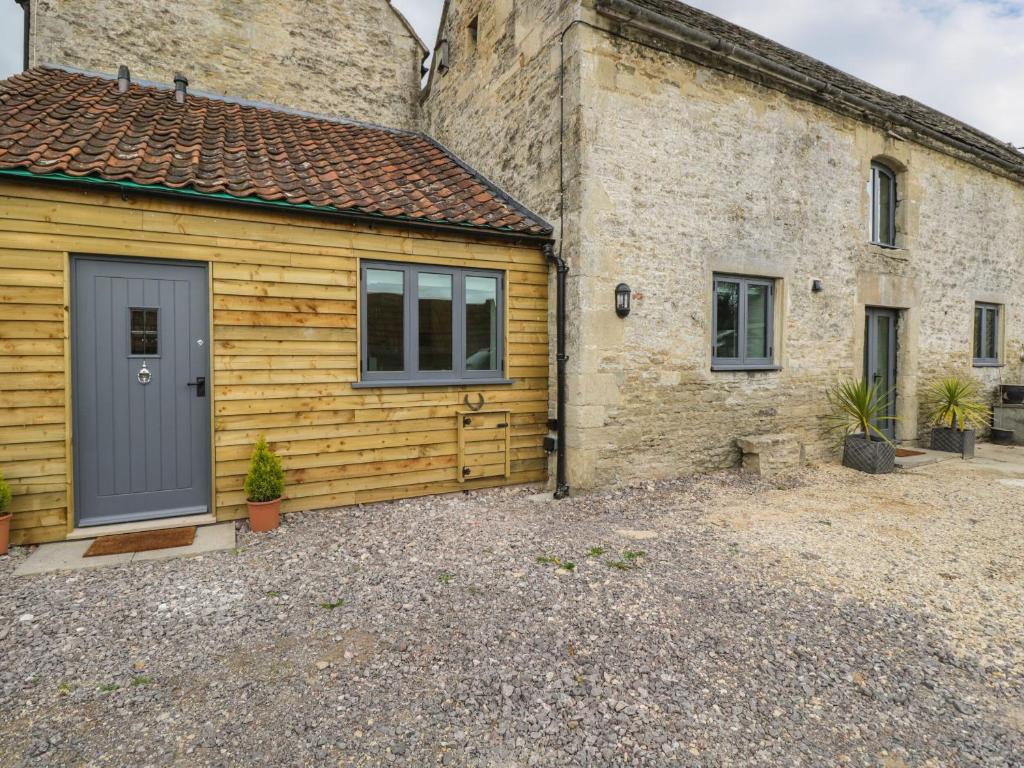 une maison avec un garage et un bâtiment en pierre dans l'établissement Chequers Barn, à Corsham