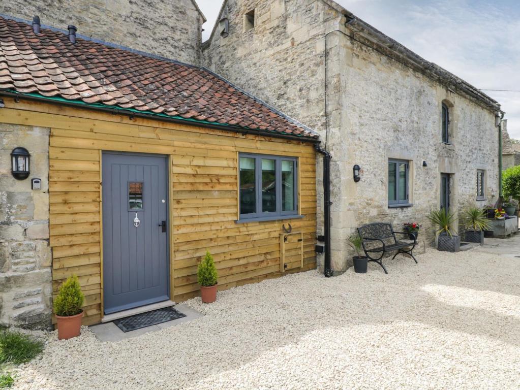 a wooden building with a blue door in front at Chequers Barn in Corsham