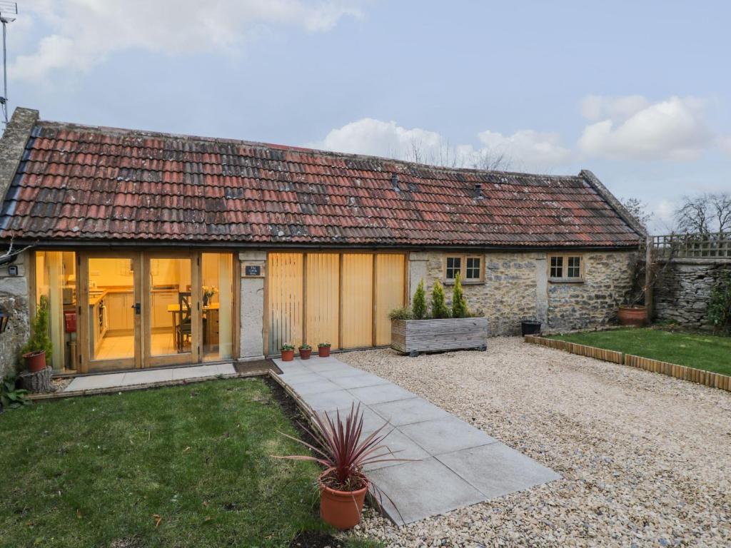 una pequeña casa de piedra con un camino delante de ella en The Cattle Byre, en Corsham