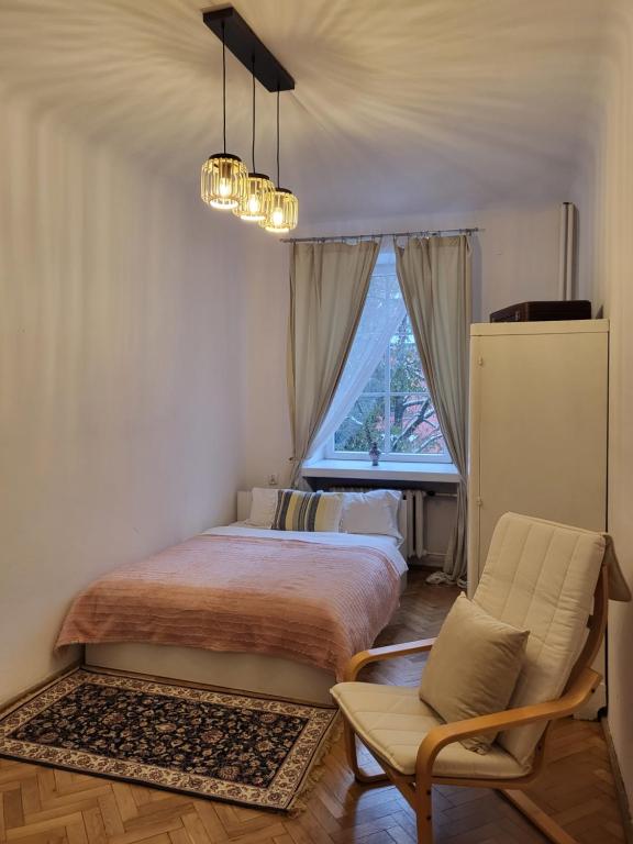 a bedroom with a bed and a chair and a window at Apartamenty - MI Stare Miasto in Warsaw