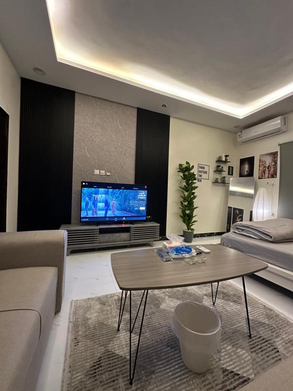 شقة أنيقة في العليا في الرياض: غرفة معيشة مع أريكة وطاولة وتلفزيون