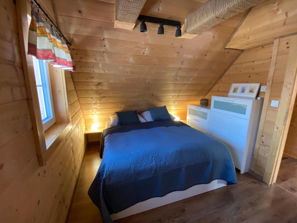 een slaapkamer met een blauw bed in een houten hut bij Chata Dante in Liptovský Mikuláš
