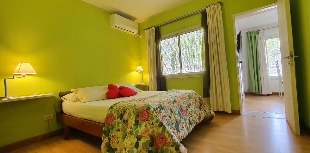 sypialnia z zielonymi ścianami i łóżkiem z czerwonymi poduszkami w obiekcie URBANA Departamento 1d. Zona Mujer urbana, Allende, Kempes. w Córdobie