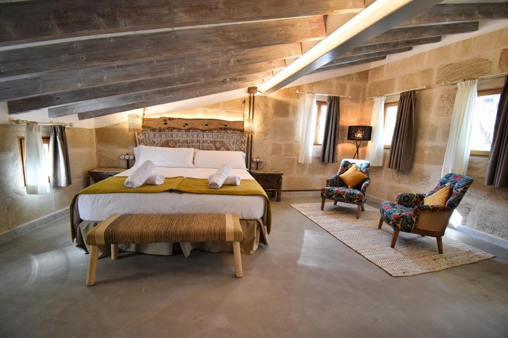 a bedroom with a large bed and two chairs at Calvario Plaza Hotel in Pollença