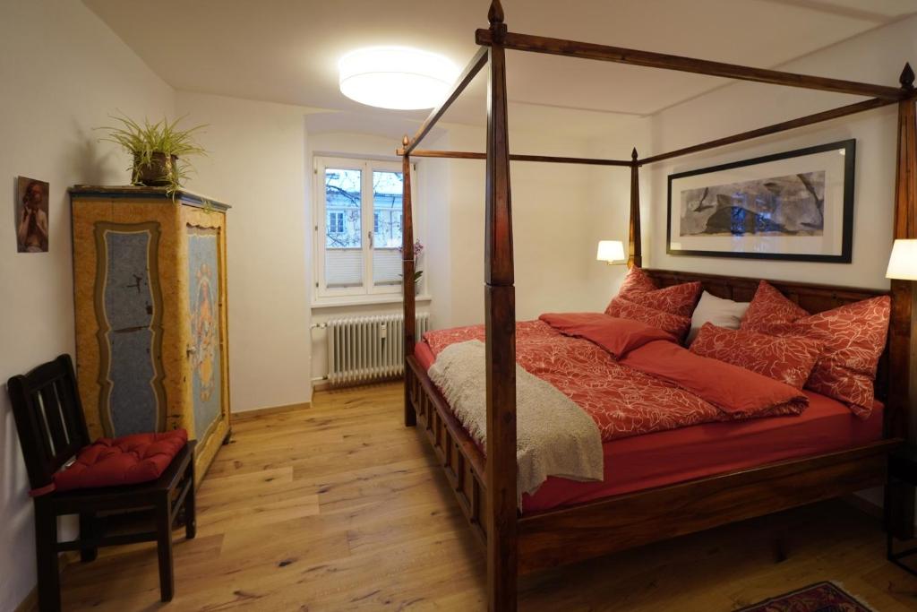 een slaapkamer met een hemelbed met rode kussens bij Altstadt Apartment am Schergentor in Hall in Tirol