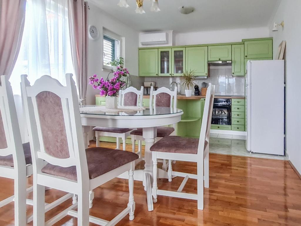 una cocina con armarios verdes y una mesa y sillas blancas. en Sea-view Apartments Klara - Viganj, en Viganj