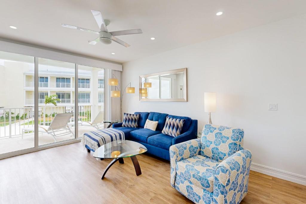 a living room with a blue couch and a chair at Beach Club Tidal Wave #25 in Key Colony Beach