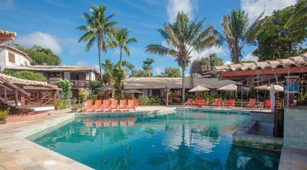 een zwembad in een resort met stoelen en palmbomen bij Hotel Solar do Imperador in Porto Seguro