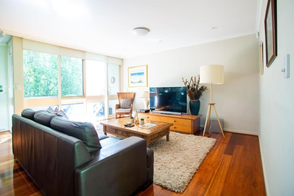 - un salon avec un canapé et une télévision dans l'établissement Leafy Toorak two bedroom executive apartment, à Melbourne