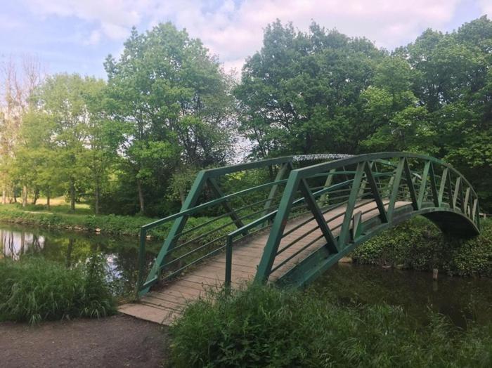 un pont vert sur une rivière dans un parc dans l'établissement ST greg pause, à Rennes