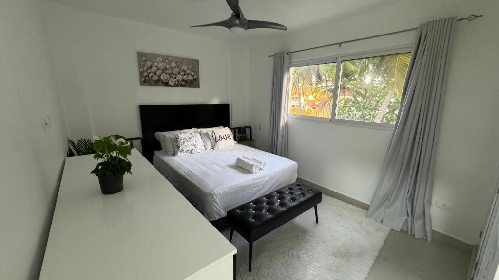 a small bedroom with a bed and a window at Oceanfront Cristamar Apartment in Cabarete
