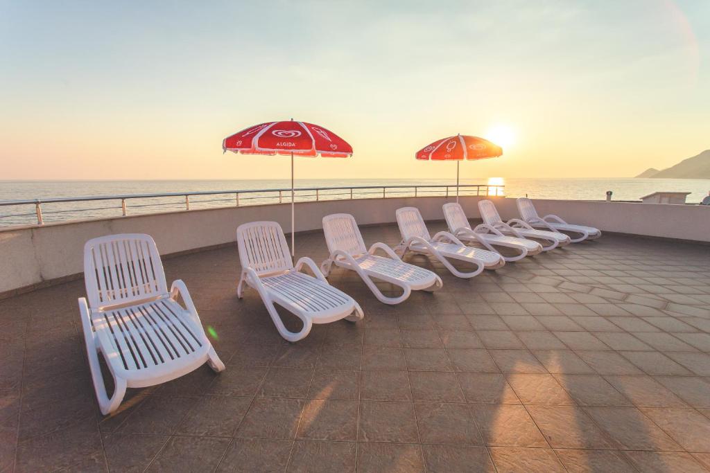 a row of white chairs and umbrellas on a pier at Apartments Deus in Dobra Voda