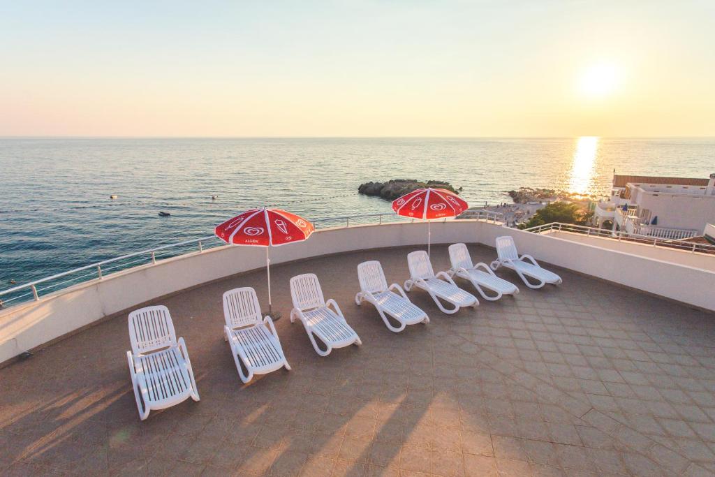 a group of chairs and umbrellas on a balcony with the ocean at Apartments Deus in Dobra Voda