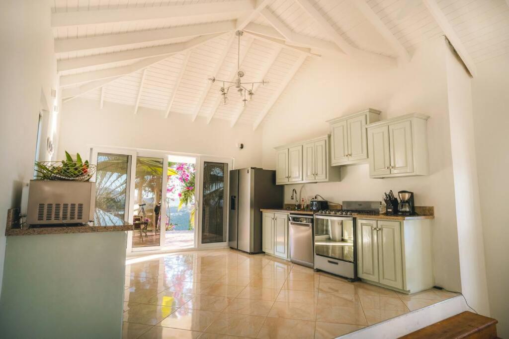 eine Küche mit weißen Schränken und Fliesenboden in der Unterkunft Amazing mountain top home with pool in Marigot-Bucht