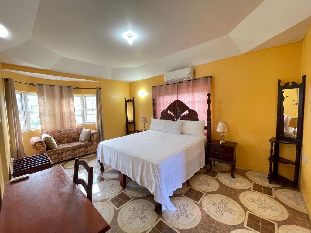 a bedroom with a white bed and a couch at Veronica Homestay Lucea Jamaica in Lucea